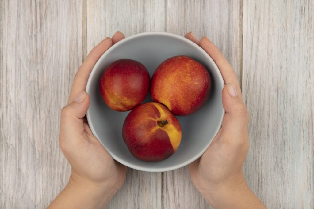 female-hands-holding-bowl-sweet-fresh-peaches