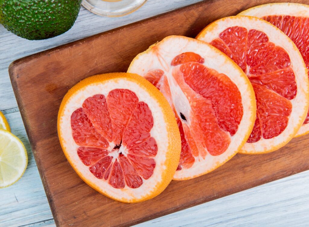 close-up-view-sliced-grapefruit-cutting-board-wooden-background
