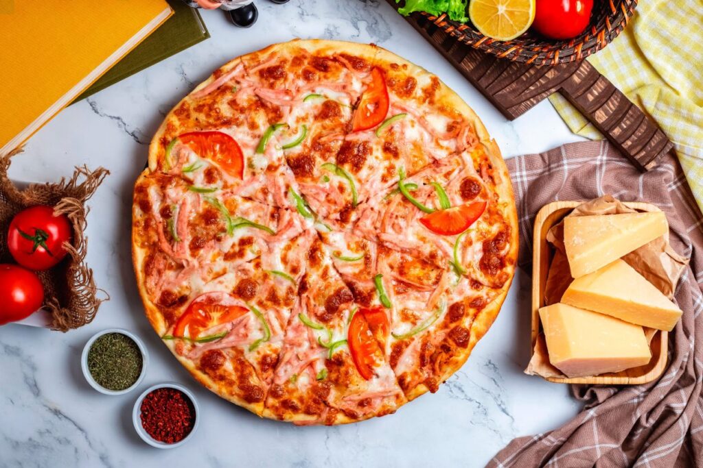 side-view-pizza-with-green-peppers-tomatoes-ham-cheese-wooden-plate-table